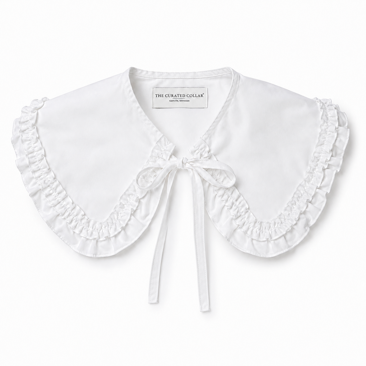 White cotton large ruffle accessory collar with a bow on a white background, branded 'The Curated Collar' Nashville TN