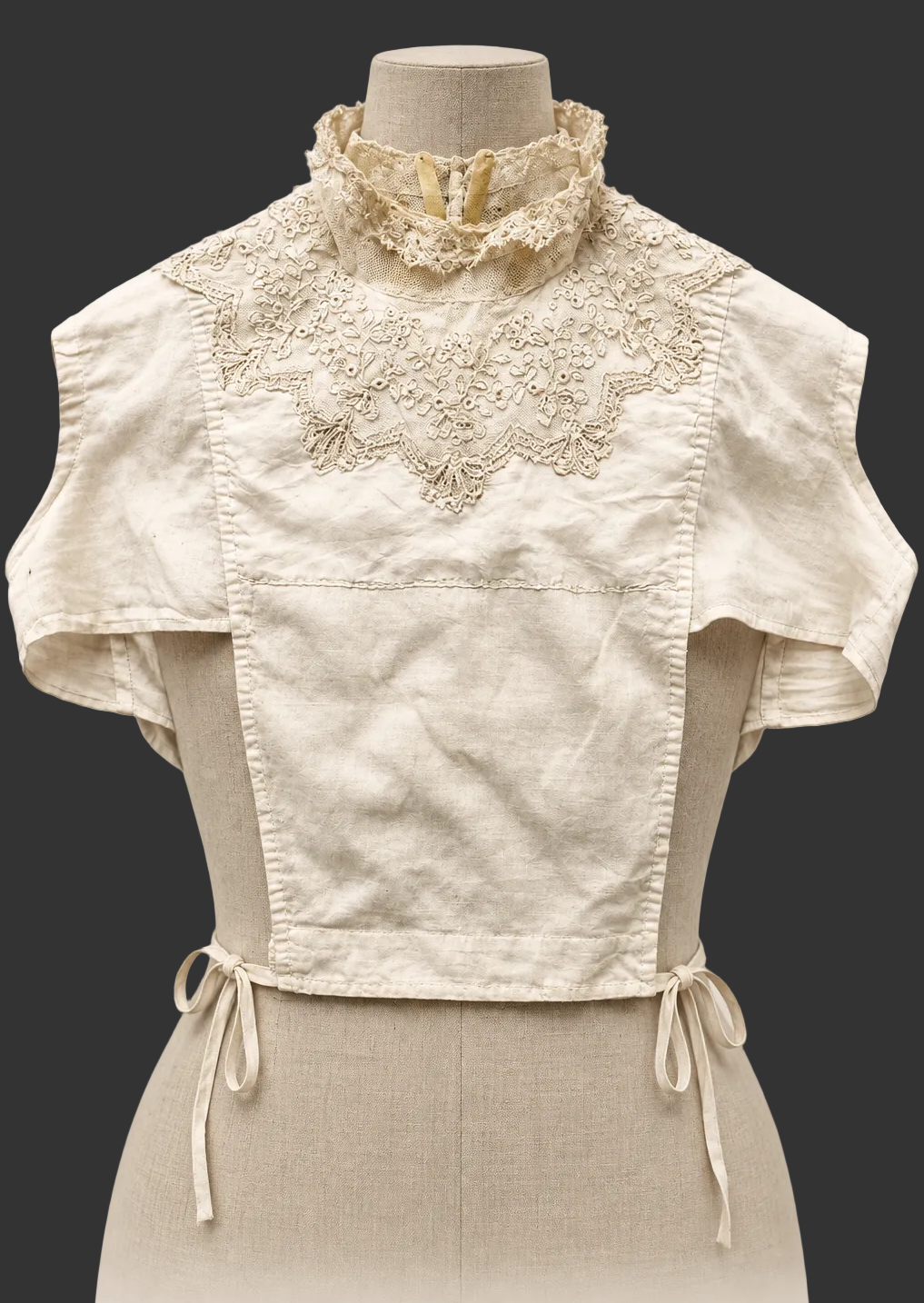 An antique-style cream linen blouse with lace yoke dickey and ruffled collar, displayed on a mannequin against a light beige background. Text at the bottom reads 'Ladies Bosom Blouse, c. 187